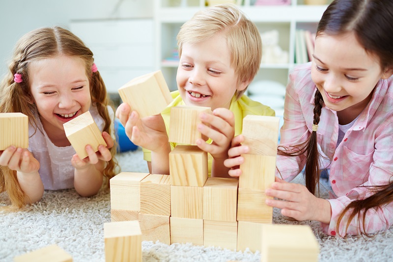 Three little friends playing with wooden bricks